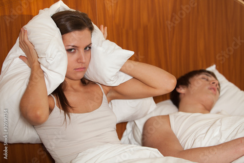 Photo: Unhappy woman and her snoring husband. Unhappy woman and her snoring husband.