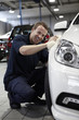 Mechanic waxing new car in showroom