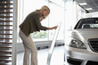 Woman looking at price list for new car in showroom