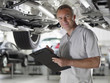 Mechanic working underneath car in auto repair shop