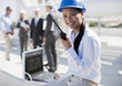 Businesswoman in hard-hat talking on walkie-talkie outdoors