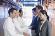 Business people shaking hands with scientists in factory