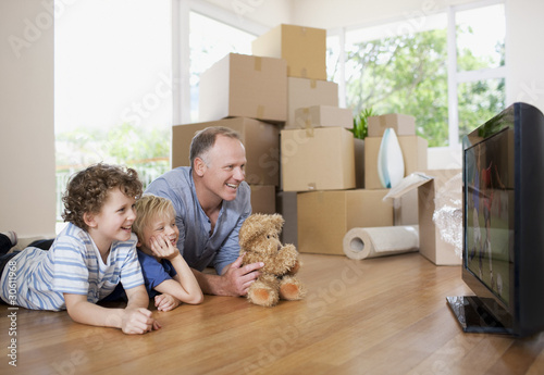 Photo: Father and children watching television in new house Father and children watching television in new house