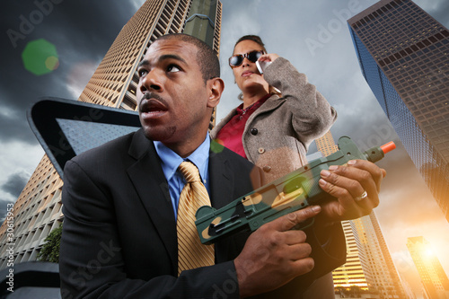 Photo: Business war game, businesspeople with gun in city. Business war game, businesspeople with gun in city.
