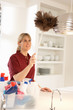 Cleaner Working In Domestic Kitchen With Feather Duster