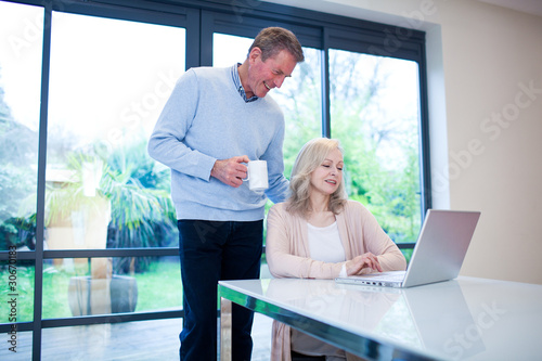 Photo: Couple at table with laptop and cup of coffee Couple at table with laptop and cup of coffee