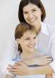 Mother with arms around preteen daughter