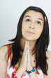 Teen girl holding clasped hands under chin, looking up, portrait