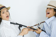 Photo: Two young female friends dressed in hats, pulling each other's ties, looking at camera Two young female friends dressed in hats, pulling each other's ties, looking at camera