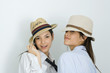 Photo: Two young female friends wearing hats and ties, smiling at camera, one looking over shoulder Two young female friends wearing hats and ties, smiling at camera, one looking over shoulder