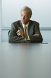 Businessman seated, furrowing brow and pointing finger