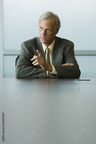 Photo: Businessman seated, furrowing brow and pointing finger Businessman seated, furrowing brow and pointing finger