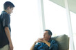 Grandfather talking with grandson on porch, hands clasped, both looking at each other
