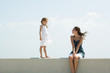 Photo: Little girl walking on ledge toward older sister, seated, both smiling at each other Little girl walking on ledge toward older sister, seated, both smiling at each other