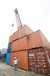 Woman standing in front of stacked industrial storage units, rear view