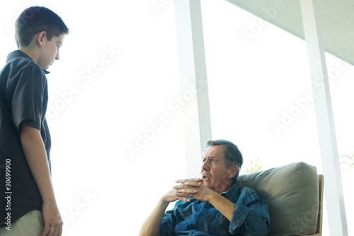 Photo: Grandfather talking with grandson on porch, hands clasped, both looking at each other Grandfather talking with grandson on porch, hands clasped, both looking at each other