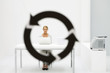 Photo: Female professional sitting in office, looking at camera through arrow symbol in foreground Female professional sitting in office, looking at camera through arrow symbol in foreground