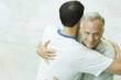 Man embracing adult son, smiling at camera, high angle view