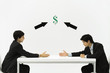 Photo: Two businessmen face to face, reaching to shake hands, dollar sign and arrows between them Two businessmen face to face, reaching to shake hands, dollar sign and arrows between them