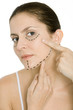 Woman pointing at plastic surgery markings on face, looking at camera