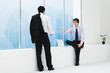 Two businessmen facing each other, one sitting on ledge, one standing