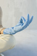 Person wearing rubber glove, sitting in lotus position, cropped view of hand