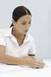 Woman reading document, holding pen