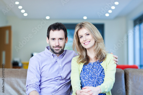 Photo: Smiling couple sitting on couch Smiling couple sitting on couch