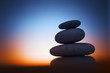 Zen stones at night over sunrise background Zen stones at night over sunrise background