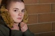 Photo: Girl With Shaved Head Holding Hood Of Coat&Leaning On Brick Wall Girl With Shaved Head Holding Hood Of Coat&Leaning On Brick Wall