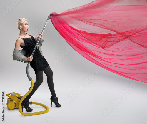 Photo: Young woman using vacuum cleaner. Isolated. Young woman using vacuum cleaner. Isolated.