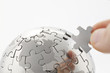 business concept with a hand building puzzle globe on white, spa