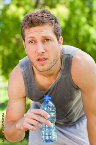Photo: Sporty man drinking water in the park Sporty man drinking water in the park