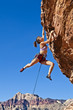 Female rock climber clinging to a cliff.