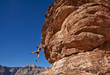 Female rock climber clinging to a cliff.