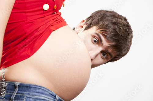Photo: Surprised man peek out from behind the pregnant belly Surprised man peek out from behind the pregnant belly