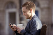 A young man sitting on a bench, using his mobile phone
