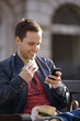 A young man sitting on a bench, using his mobile phone