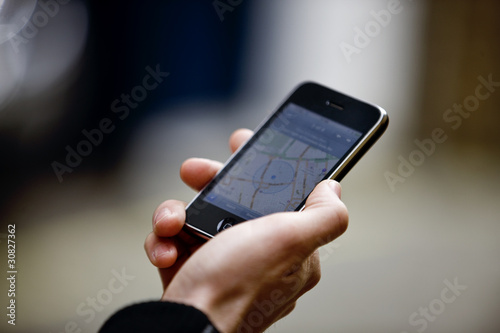 Photo: A young man looking at a map on his mobile phone, close-up A young man looking at a map on his mobile phone, close-up