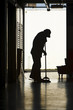 Silhouette of man moping floor