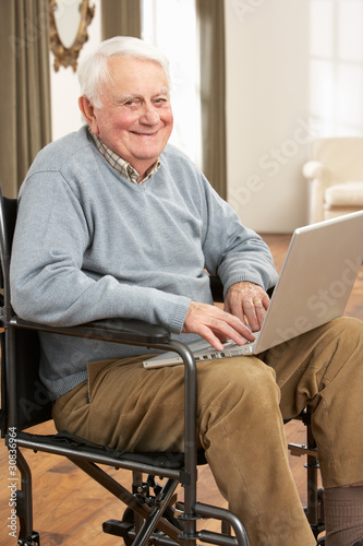 Photo: Disabled Senior Man Sitting In Wheelchair Using Laptop Disabled Senior Man Sitting In Wheelchair Using Laptop