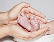 Mother holding two feet of  baby loving caring