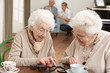 Two Senior Women Playing Dominoes At Day Care Centre
