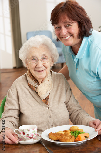 Photo: Senior Woman Being Served Meal By Carer Senior Woman Being Served Meal By Carer