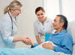 Foto: doctor shakes hands with patient in hospital bed doctor shakes hands with patient in hospital bed