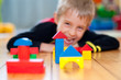 Little boy playing with wooden construction cubes