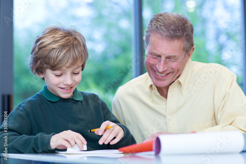 Foto: Grandfather watching grandson doing his homework Grandfather watching grandson doing his homework