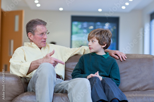 Photo: Grandfather talking to grandson on couch Grandfather talking to grandson on couch