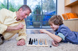 Grandfather playing chess with grandson on rug