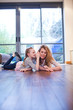 Mother and daughter laying on wooden floor whispering
